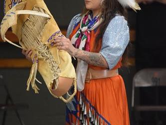 A woman dressed in native american cultural dress holding a cradleboard