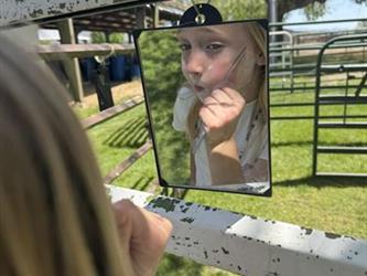 A student using a mirror pretending to shave how the pioneers would